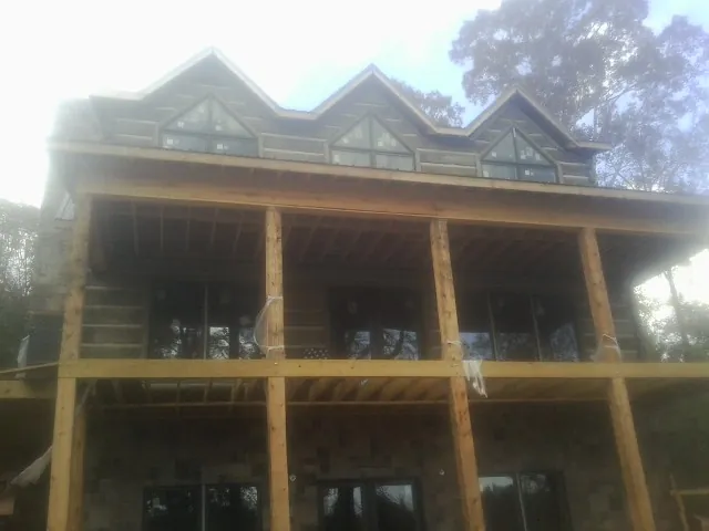 Dormers and porch framing on a large log home under construction — Roof Coating work by our crew in Austin