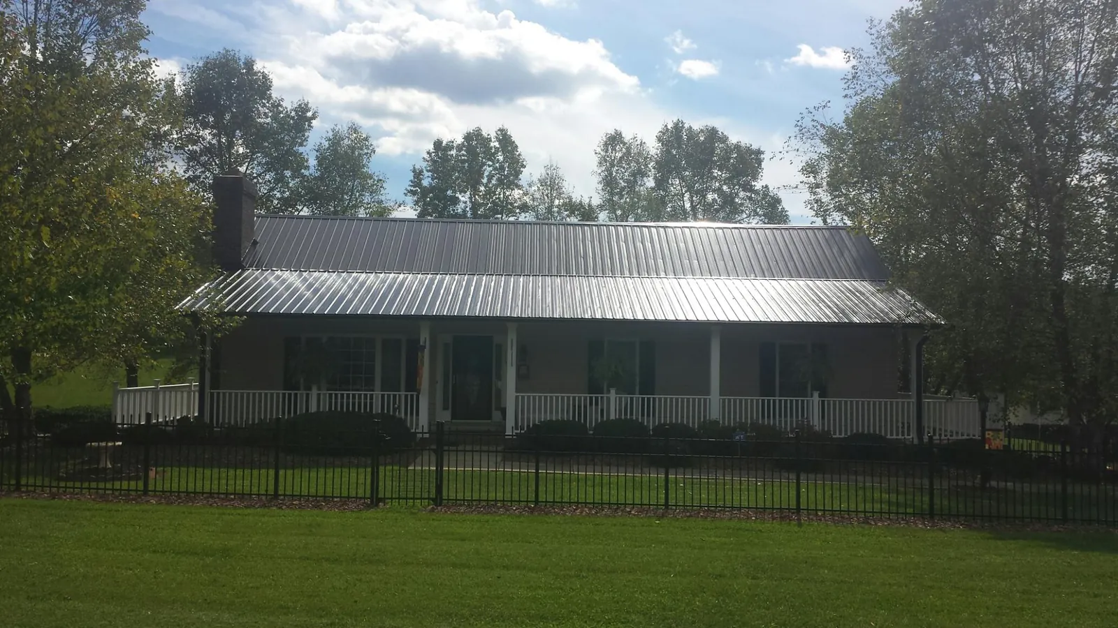 Gray metal roof on a brick ranch with a full width front porch — Gutter Guard Installation work by our crew in Austin