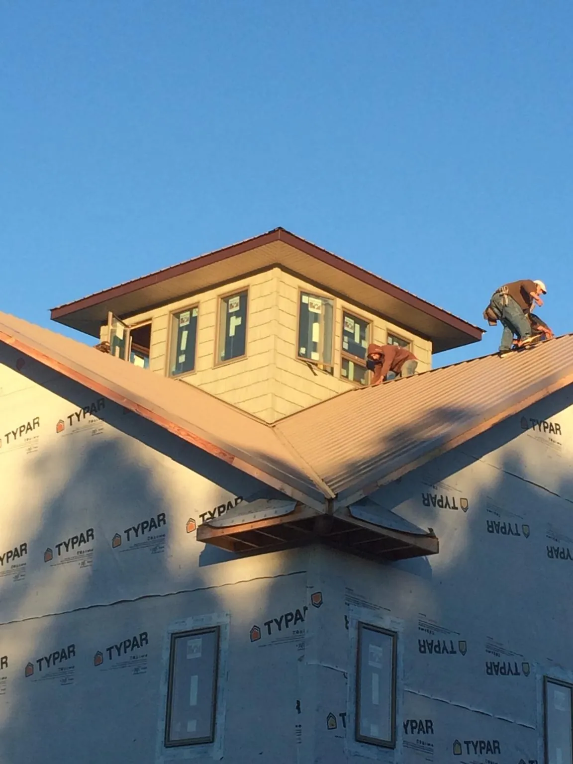 Roofers working around a rooftop cupola on a new metal roof at sunset — Roof Waterproofing in Austin by Roofing Brothers